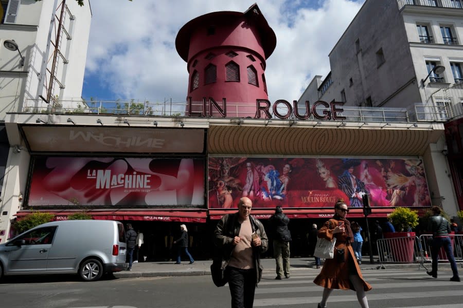 People walk past the Moulin Rouge (Red Mill) Thursday, April 25, 2024 in Paris. The windmill from the Moulin Rouge, the 19th century Parisian cabaret, has fallen off the roof overnight along with some of the letters in its name. (AP Photo/Thibault Camus)