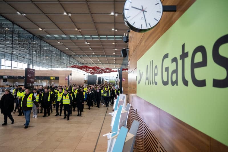 Strikers walk through the terminal at Berlin Brandenburg Airport BER, one of 11 major German airports that have started a one-day strike. Christophe Gateau/dpa