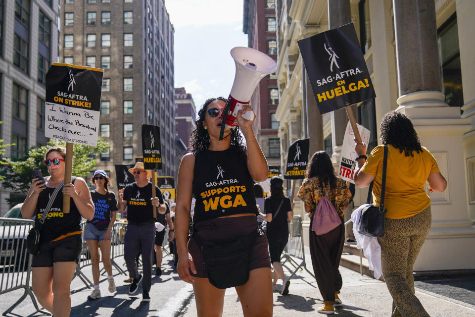 A strike captain, center, leads the chants as strikers walk a picket line outside Warner Bros., Discovery, and Netflix offices in Manhattan, Friday, Aug. 18, 2023. The WGA and SAG-AFTRA held a joint Latine Picket, presented by the WGAE Latine Writers Salon, the WGAW Latinx Writers Committee, and the SAG-AFTRA National Latino Committee. Late Tuesday, Hollywood studios made their offer to striking writers public for the first time. (AP Photo/Mary Altaffer)