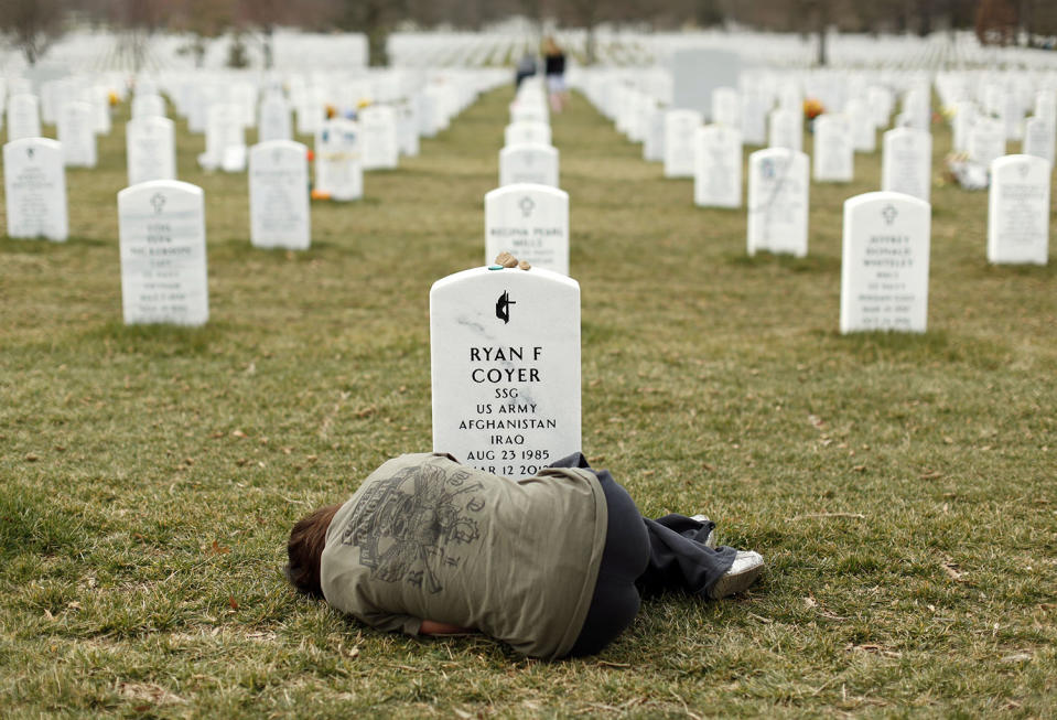 <p>Lesleigh Coyer, 25, of Saginaw, Michigan, lies down in front of the grave of her brother, Ryan Coyer, who served with the U.S. Army in both Iraq and Afghanistan, at Arlington National Cemetery in Virginia, on March 11, 2013. Coyer died of complications from an injury sustained in Afghanistan. (Photo: Kevin Lamarque/Reuters) </p>