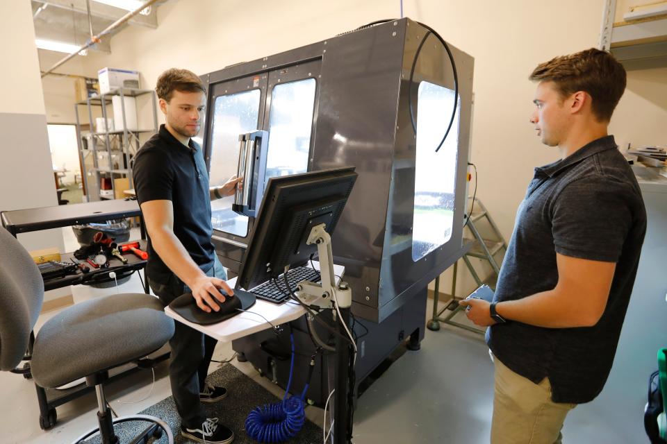 Nathaniel Fernandes and his brother Jordan Fernandes work on the CNC machine at the new ProtoXYZ offices at the DeMello International Center on Union Street in New Bedford.