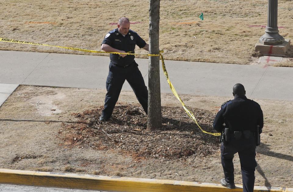 A police officers remove yellow police tape from the area surrounding Gould Hall at the University of Oklahoma in Norman, Okla., Wednesday, Jan. 22, 2014. The University of Oklahoma says authorities found no evidence of shots being fired on campus and no injuries have been reported. (AP Photo/Sue Ogrocki)