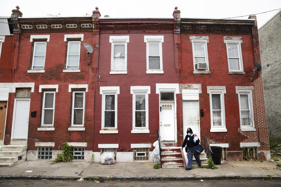 United States Postal Service carrier Henrietta Dixon walks her route to deliver mail in Philadelphia, Wednesday, May 6, 2020. On Dixon's mail route in North Philadelphia, every house has a story. (AP Photo/Matt Rourke)