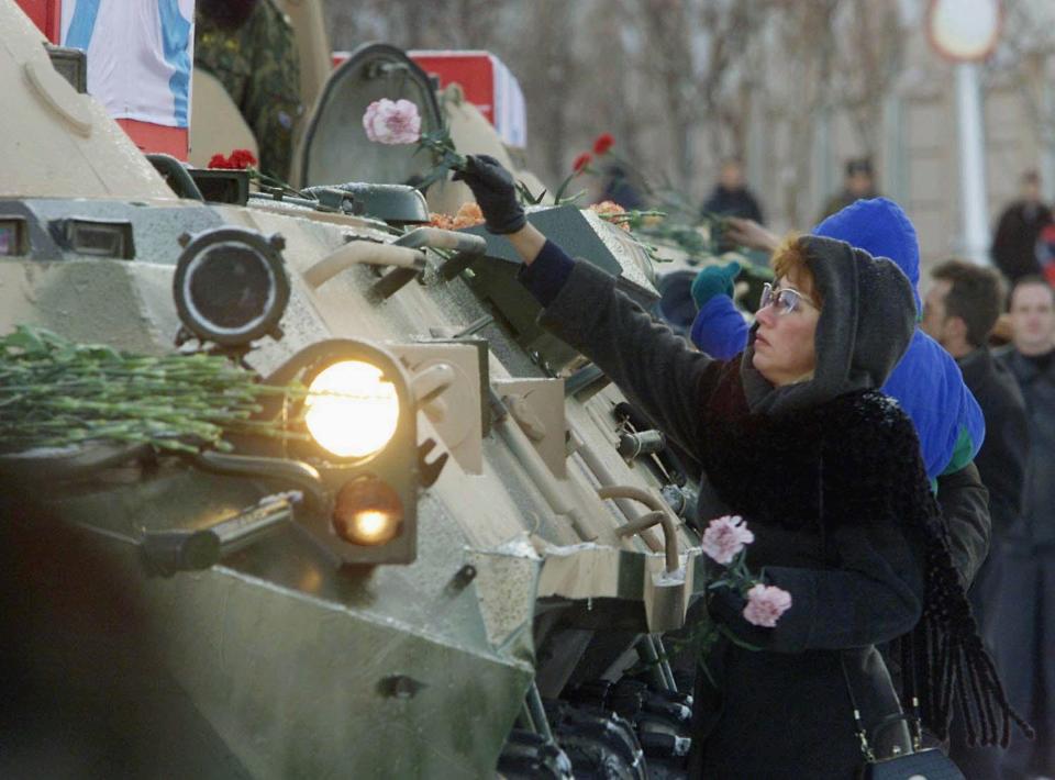 Eine Frau legt am 29. Oktober 2000 Blumen auf den Sarg eines Kursk-Besatzungsmitglieds, der auf einem Panzerfahrzeug abtransportiert wird (Bild: Ivan Sekretarev/Pool/AFP)