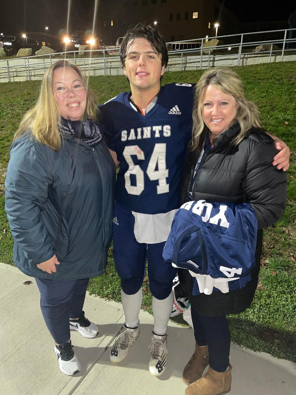 St. Thomas Aquinas graduate Joey Pickett, center, with his aunt Sarahjayne Howland, left, and his mother, Melissa, after a Saints' football game last fall. Pickett will play for New Hampshire in Saturday's annual Shrine Maple Sugar Bowl game against Vermont in honor of Howland, who was burned at the age of 5, and received care through her teenage years at Shriners Hospital.