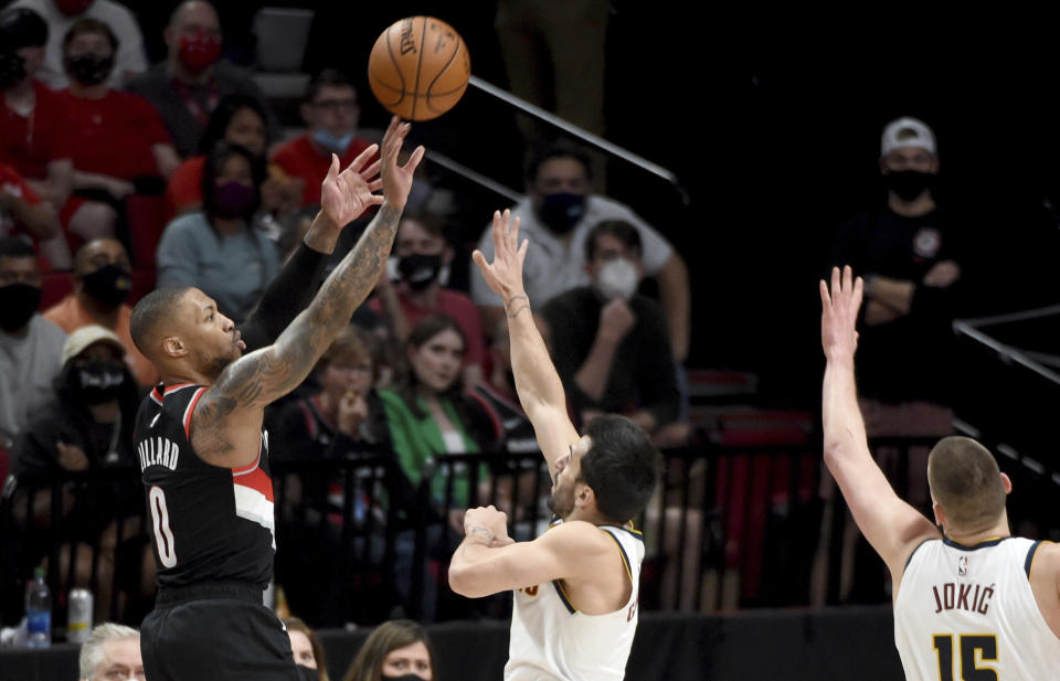 Portland Trail Blazers guard Damian Lillard, left, hits a shot over Denver Nuggets guard Facundo Campazzo, center, and center Nikola Jokic, right, during the first half of Game 4 of an NBA basketball first-round playoff series in Portland, Ore., Saturday, May 29, 2021. (AP Photo/Steve Dykes)