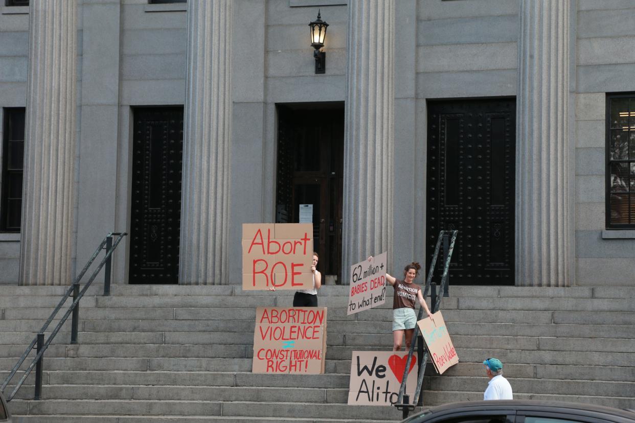 Anti-abortion protesters hold signs on the steps of the Customs House across the street from Tuesday's abortion-rights rally at Savannah City Hall.