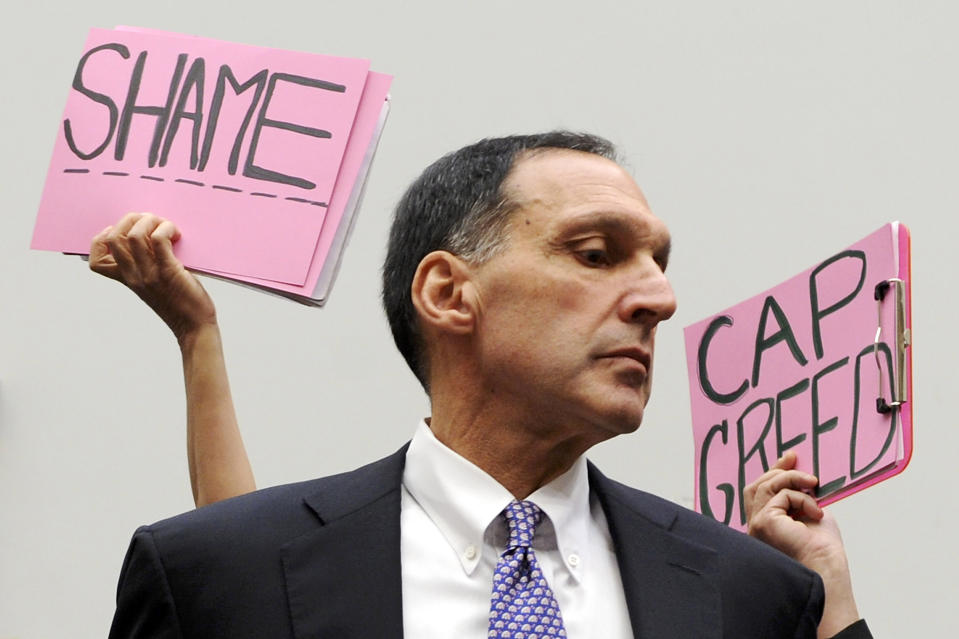 Protesters hold signs behind Richard Fuld, former Chairman and Chief Executive of Lehman Brothers Holdings, on Capitol Hill in Washington, October 6, 2008. REUTERS/Jonathan Ernst