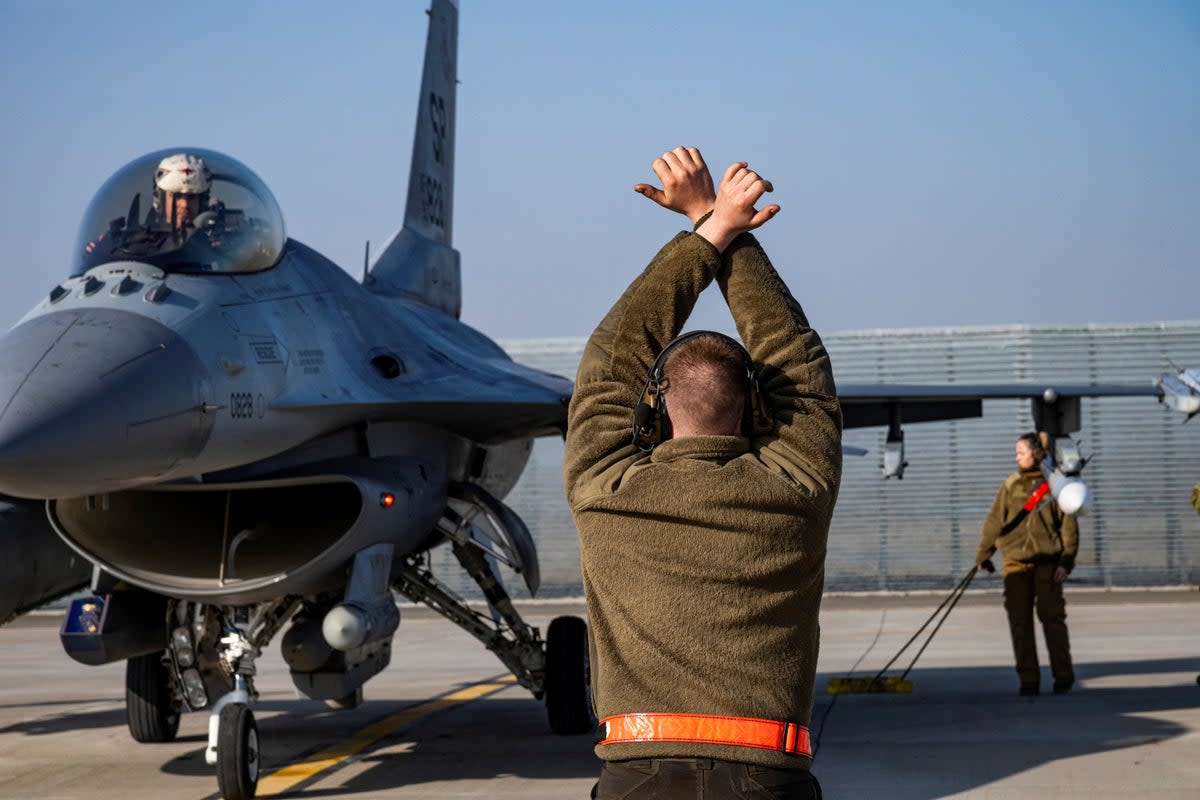 A US Air Force airman marshals an F-16 Fighting Falcon aircraft at the 86th Air Base near Fetesti, Romania, on February 17, 2022 (via REUTERS)