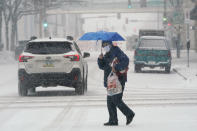 A pedestrian crosses a snow covered street, Monday, Jan. 25, 2021, in downtown Des Moines, Iowa. A major winter storm is expected to blanket a large swath of the middle of the country with snow Monday and disrupt travel as more than a foot of snow falls in some areas. (AP Photo/Charlie Neibergall)