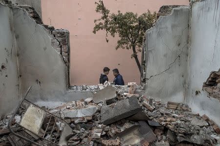 People walk by a destroyed house in Kumanovo, Macedonia, May 11, 2015. REUTERS/Marko Djurica