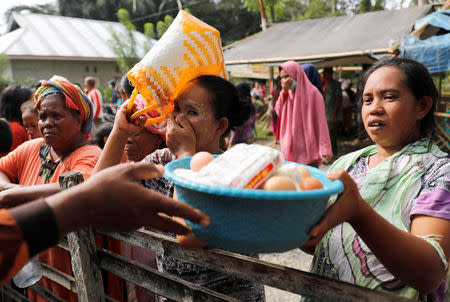 A villager holds egg, rice and noodles during an aid distribution at the epicentre of a devastating earthquake at Lende Tovea village in Donggala, Indonesia Sulawesi island, October 6, 2018. REUTERS/Beawiharta