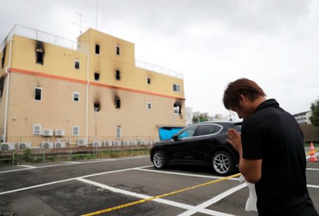 A man prays outside the Kyoto Animation building which was torched by arson attack, in Kyoto