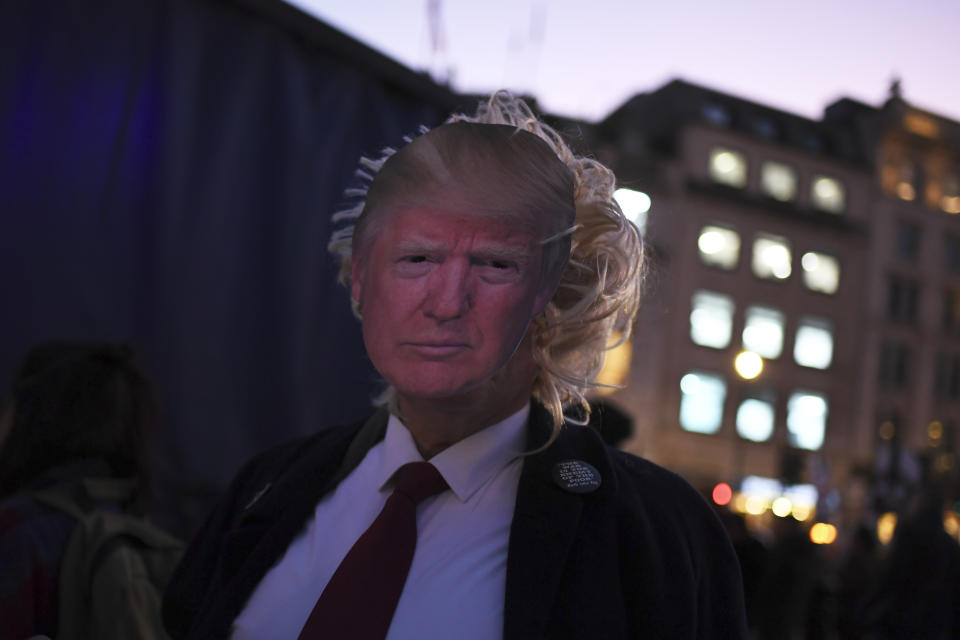 A demonstrator wears a mask with a picture of U.S. President Trump during a demonstration against the NATO summit and Trump's visit, in London, Tuesday, Dec. 3, 2019. Trump and his NATO counterparts were gathering in London Tuesday to mark the alliance's 70th birthday amid deep tensions as spats between leaders expose a lack of unity that risks undermining military organization's credibility. (AP Photo/Alberto Pezzali)