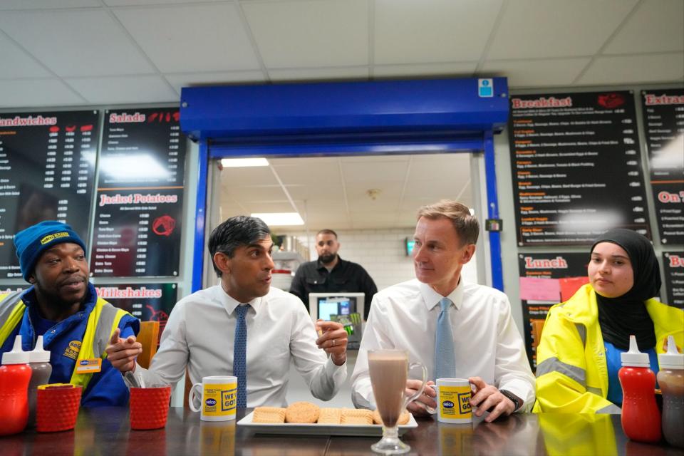 Rishi Sunak, centre and have a drink and biscuits with employees during a visit to a builders warehouse in London on Wednesday (AP)