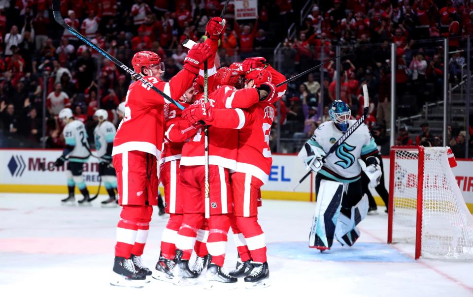 Teammates celebrate with center Dylan Larkin, who scored against Seattle, during the third period of the Wings' 5-4 overtime loss on Tuesday, Oct. 24, 2023, at Little Caesars Arena.