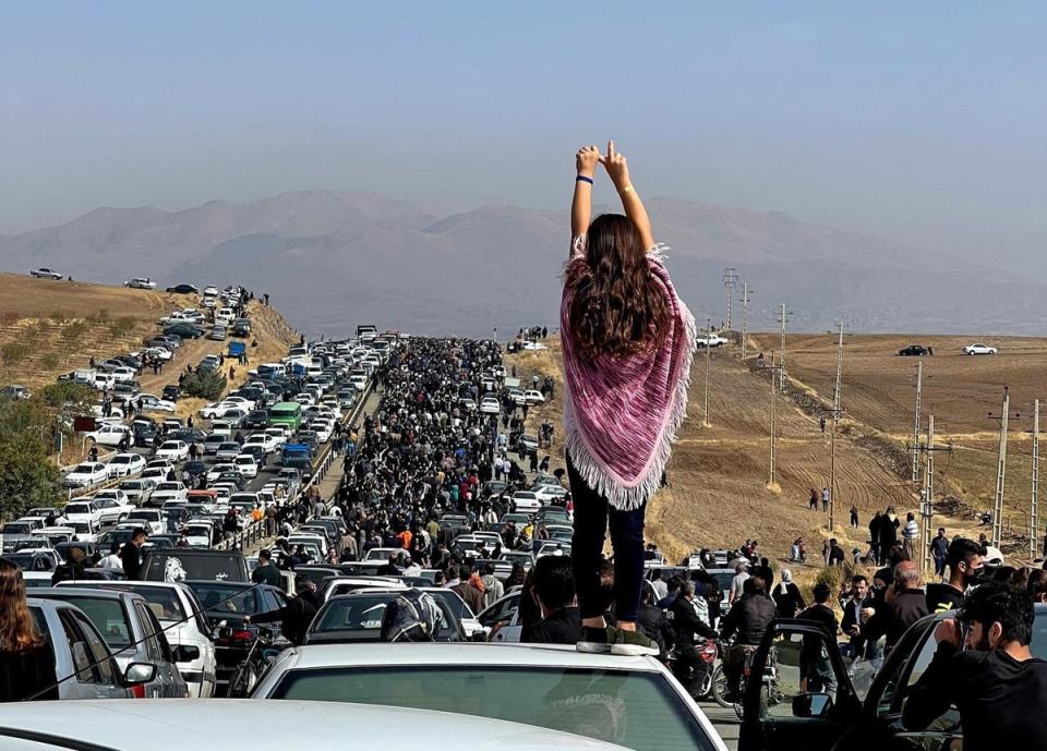 A woman standing on top of a vehicle as thousands make their way towards Aichi cemetery in Saqez, Mahsa Amini’s home town in the western Iranian province of Kurdistan, to mark 40 days since her death (UGC/AFP via Getty Images)