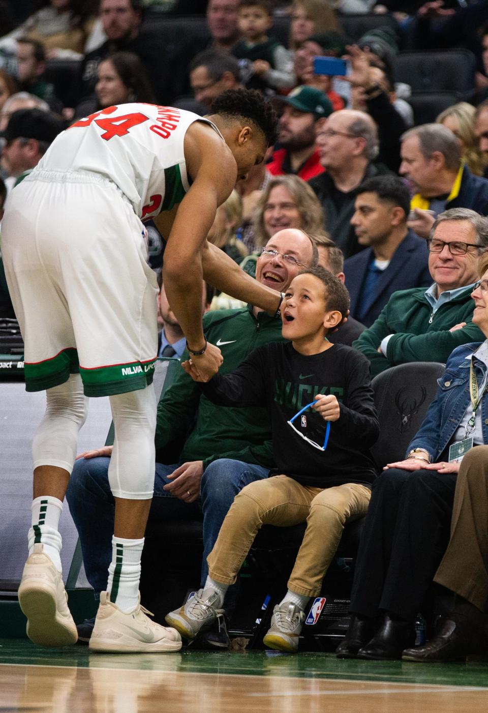 Giannis Antetokounmpo greets a young fan before a game at Fiserv Forum in December 2018.