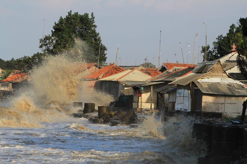 Houses are hit by a wave on a beach during tide in Indramayu