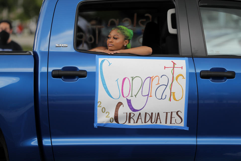 Allyn McKenney, sister of graduate Glen McKenney watches as the New Orleans Charter Science and Math High School class of 2020 holds a drive-in graduation ceremony as a result of the COVID-19 pandemic, outside Delgado Community College in New Orleans, Wednesday, May 27, 2020. Students and family got out of their cars to receive diplomas one by one, and then held a parade of cars through city streets. (AP Photo/Gerald Herbert) Allyn McKinney, sister of Glen McKenney