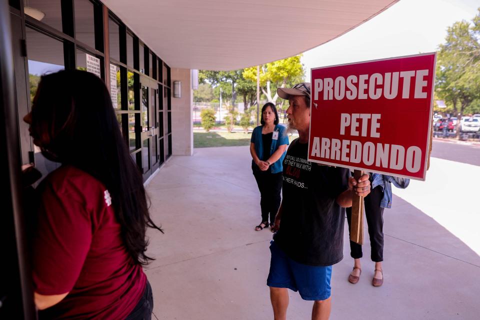 Michael Brown, a Robb Elementary parent, carries a sign reading "Prosecute Pete Arredondo" into an Uvalde Consolidated Independent School District meeting at Uvalde High School on July 18.