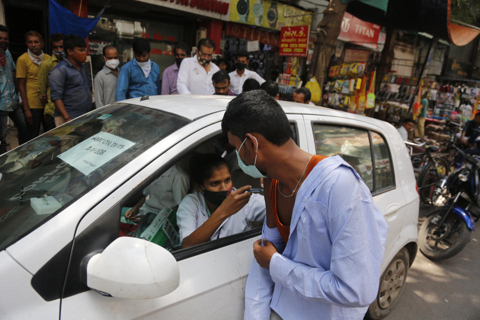 A health worker administers the vaccine for COVID-19 during a vaccination drive at a market place in Ahmedabad, India, Friday, Sept. 24, 2021. (AP Photo/Ajit Solanki)