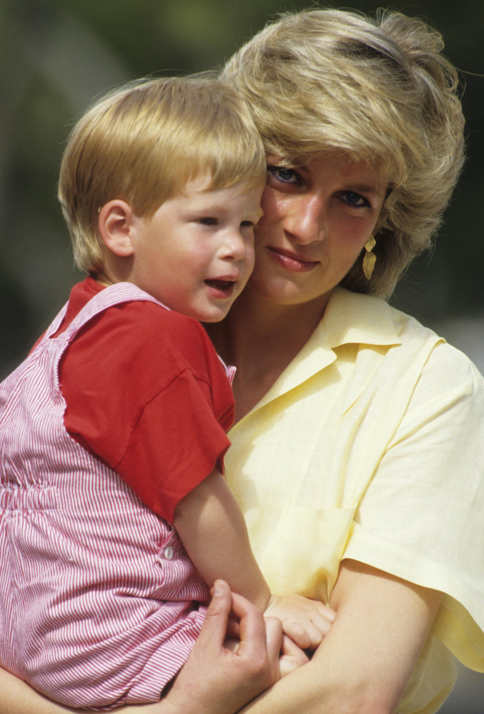 A young Prince Harry being held by Princess Diana