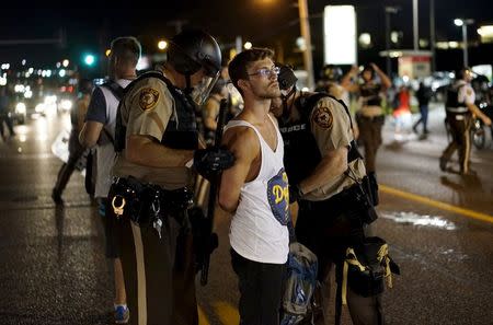Police hold a protester who was detained in Ferguson, Missouri, August 10, 2015. REUTERS/Rick Wilking