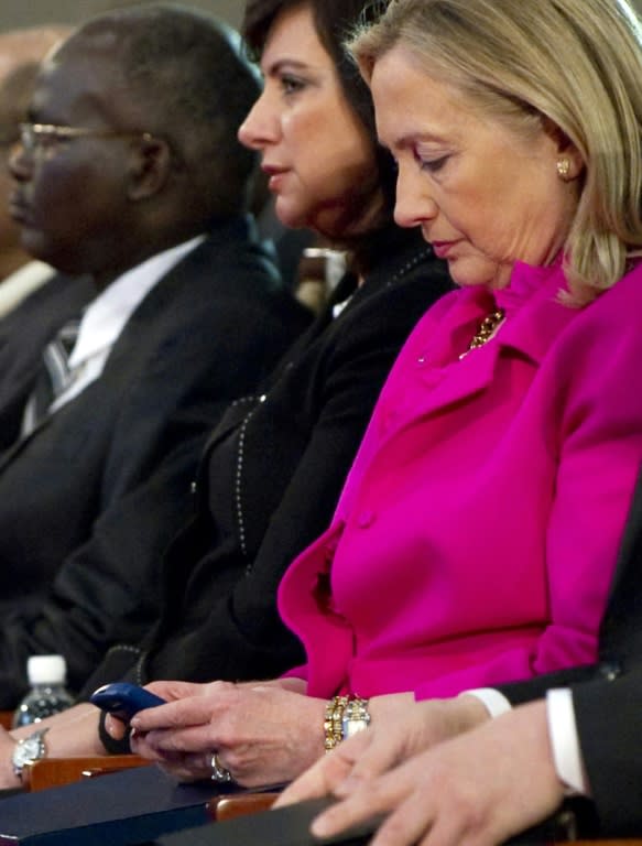 Hillary Clinton (2nd R), then US Secretary of State, checks her Blackberry phone as she attends the Fourth High Level Forum on Aid Effectiveness in Busan, Korea on November 30, 2011