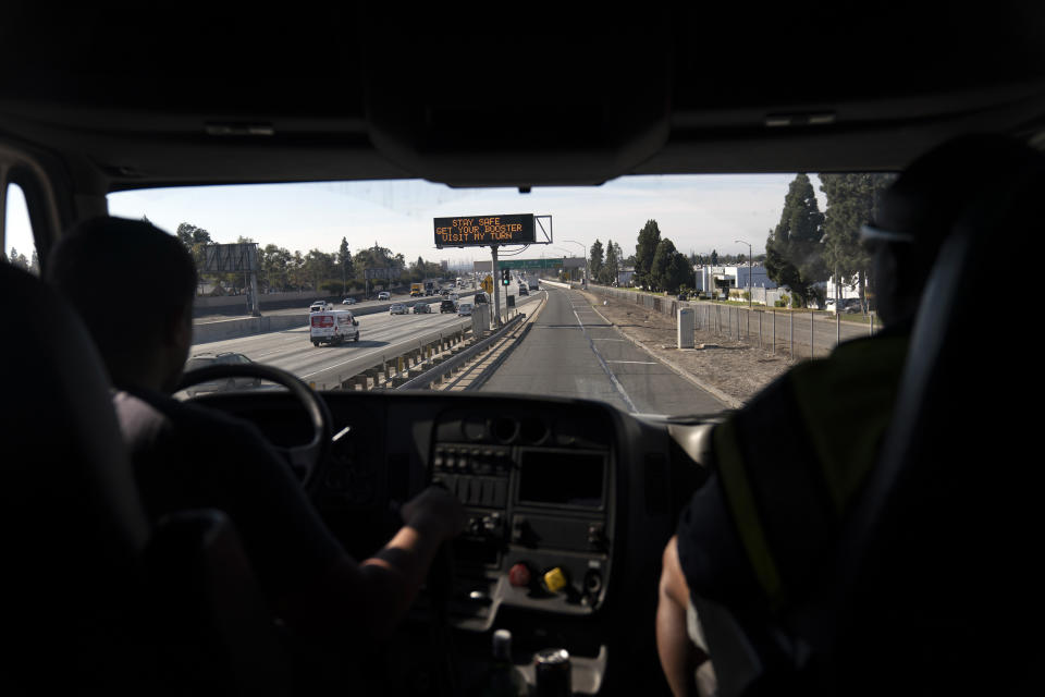 Accompanied by instructor Tony DeVeres from California Truck Driving Academy, right, student driver Edgar Lopez, 23, drives a practice truck along the freeway in Inglewood, Calif., Monday, Nov. 15, 2021. Business is booming at a truck-driving academy in suburban Los Angeles amid a nationwide shortage of long-haul drivers. The California Truck Driving Academy in Inglewood has seen annual enrollment grow by almost 20% since last year. (AP Photo/Jae C. Hong)