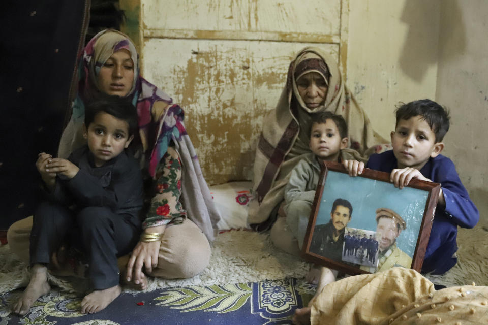 A son of Mohammed Hassan, a Pakistani porter who died on July 27 during a summit of K2, holds a portrait of his father and grandfather, with Hassan's mother, third left, and wife at their home in Tasar, a village in the Shigar district in the Gilgit-Baltistan region of northern Pakistan, Saturday, Aug. 12, 2023. An investigation has been launched into the death of a Hassan near the peak of the world's most treacherous mountain, a Pakistani mountaineer said Saturday, following allegations that dozens of climbers eager to reach the summit had walked past the man after he was gravely injured in a fall. (AP Photo/M.H. Balti)