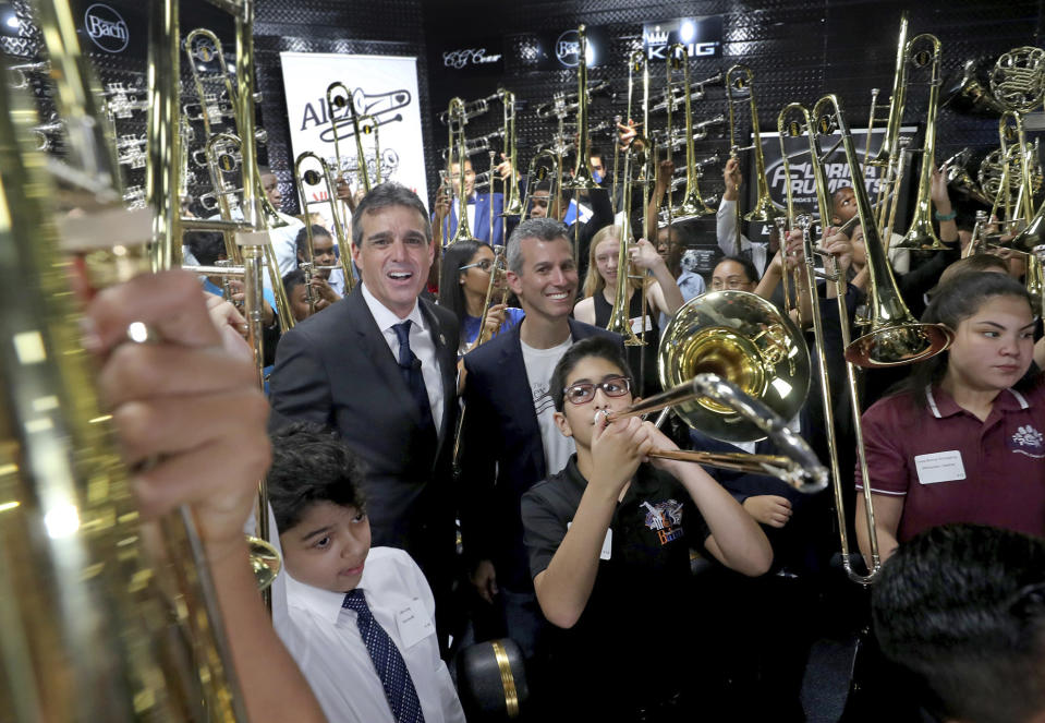 Fred Schiff, the owner of All County Music and Max Schachter, the father of Alex Schachter, stands with the recipients of the Alex Tribute Trombones on Saturday, May 11, 2019 in Tamarac, Fla. All County Music honored the life of Alex Schachter, a Marjory Stoneman Douglas shooting victim, by presenting $50,000 worth of specially designed Alex Tribute Trombones to 50 band students from 50 different south Florida schools. (Mike Stocker/South Florida Sun-Sentinel via AP)