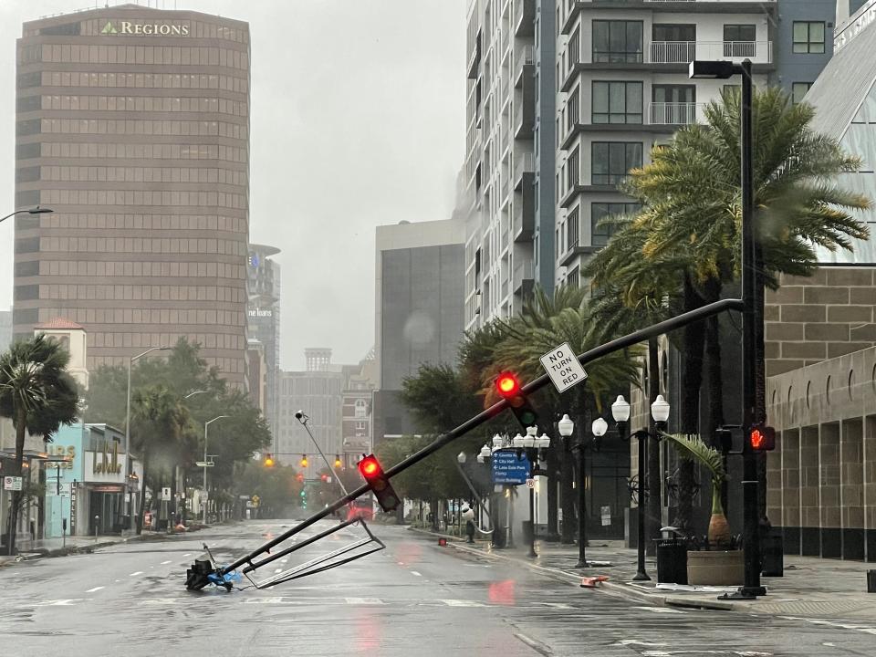 A stoplight pole blown down by Hurricane Ian winds, rests on Orange Avenue in Downtown Orlando, Fla., on Thursday, Sept. 29, 2022.   Hurricane Ian has left a path of destruction in southwest Florida, trapping people in flooded homes, damaging the roof of a hospital intensive care unit and knocking out power. (Willie J. Allen Jr./Orlando Sentinel via AP)