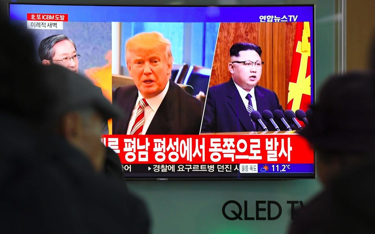 A TV screen shows pictures of US President Donald Trump and North Korean leader Kim Jong-un at a railway station in Seoul  - AFP