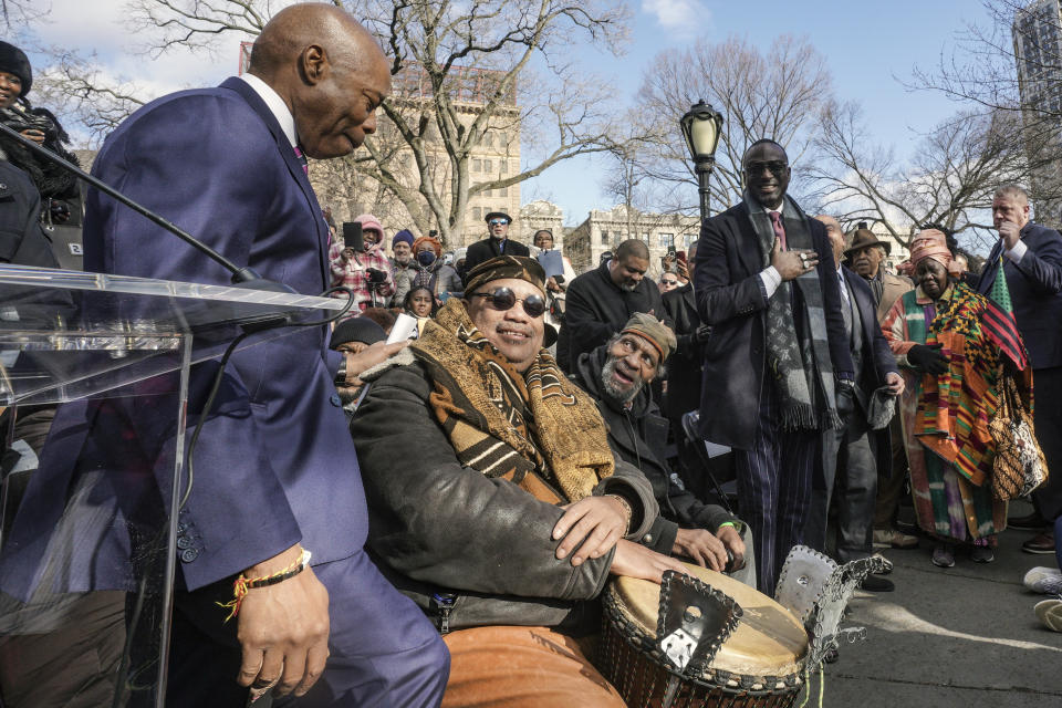 Mayor Eric Adams, left, leaves the podium to greet Yusef Salaam, standing center, one of five men exonerated after being wrongfully convicted as teenagers for the 1989 rape of a jogger in Central Park, after speaking at a ceremony to name the northeast gateway of Central Park as "The Gate of the Exonerated," Monday Dec. 19, 2022, in New York. The entrance was named to honor Salaam, Raymond Santana Jr., Kevin Richardson, Antron McCray and Korey Wise, the five men exonerated in the case. (AP Photo/Bebeto Matthews)