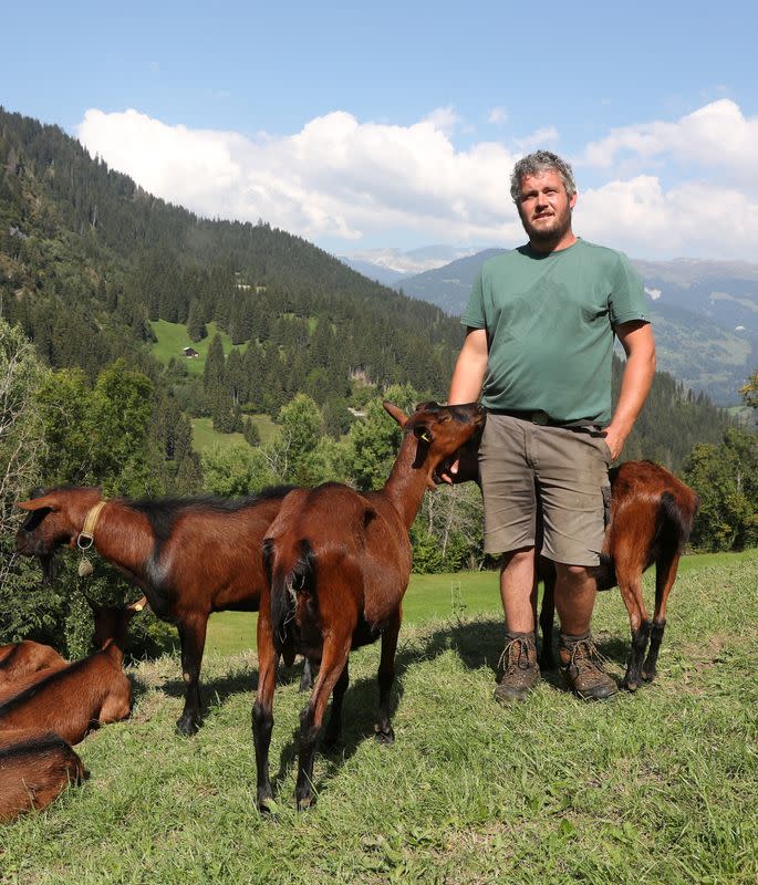 Farmer Martin Keller and his goats stand on a meadow near Ilanz