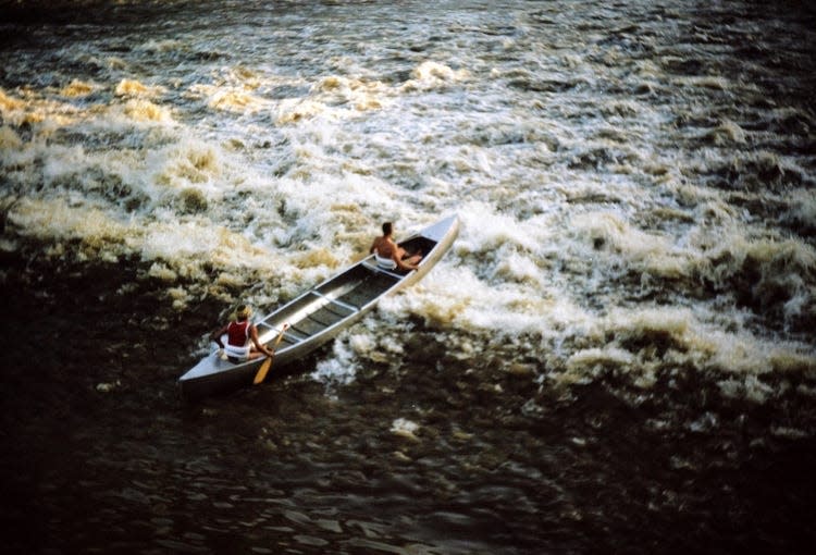 A dam is successfully crossed by Bill Malcuit and Jim Ecenbarger during a canoe trip from Dover to New Orleans.