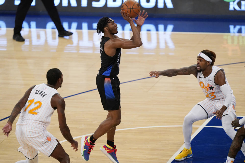 New York Knicks guard Immanuel Quickley (5) goes up for a shot with Orlando Magic forward Gary Clark (12) and Magic guard Jordan Bone (23) reacting during the first half of an NBA basketball game, Monday, Jan. 18, 2021, in New York. (AP Photo/Kathy Willens, Pool)