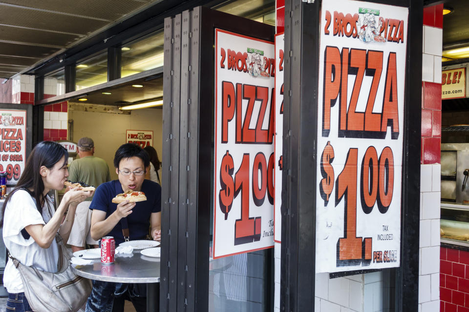 Couple eating pizza at 2 Bros Pizza in NYC. (Jeff Greenberg / Getty Images)