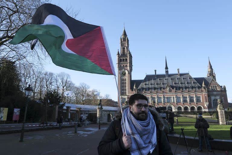 Un manifestante alza una bandera palestina frente al Palacio de la Paz, sede de la Corte Internacional de Justicia, en La Haya, Holanda, viernes 26 de abril de 2024