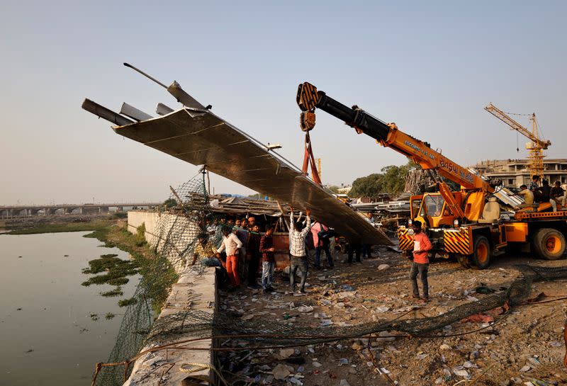 People remove debris after a suspension bridge collapsed in Morbi town