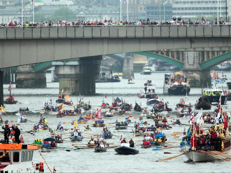 Rowbarge Gloriana (R) leads the manpowered section past HMS Belfast (L) of the Diamond Jubilee River Pageant during the Queen Elizabeth's Diamond Jubilee Pageant on the River Thames in London (AFP via Getty Images)