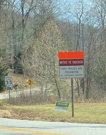 Warning signs prohibiting through trucks on Pinners Cove Road in southern Buncombe County have been in place since February 2016, but truckers continue to get stuck on its hairpin curves.