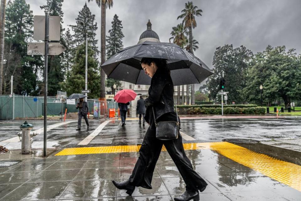 McKinley Thompson-Morley walks to work in the rain on Wednesday in downtown Sacramento near the state Capitol.