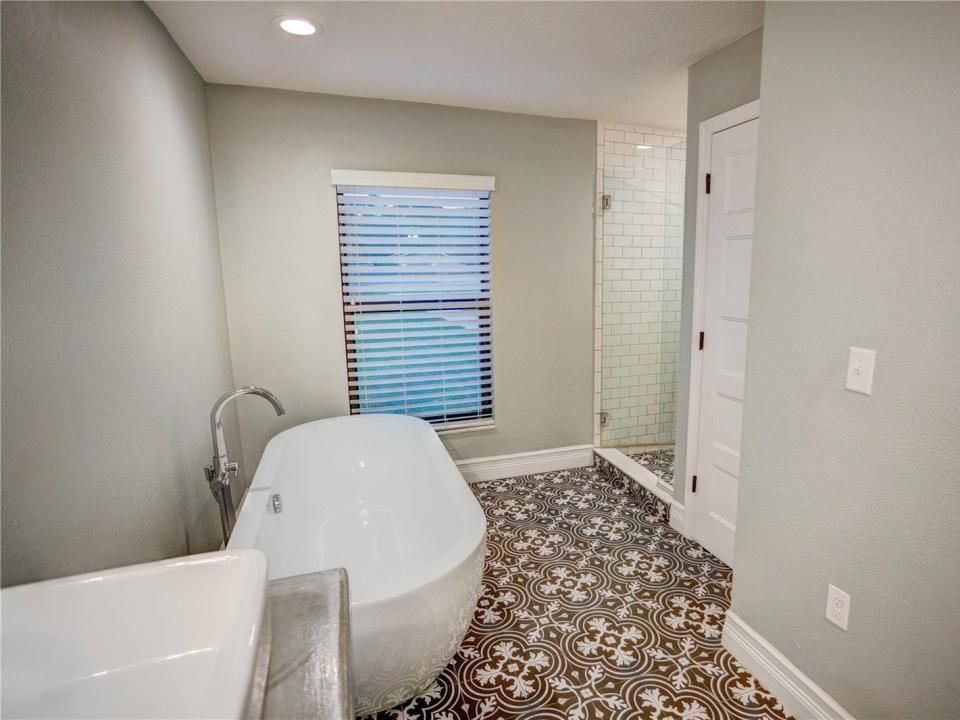 the bathroom with black pattern tiles, a soaking tub on the left, and a shower on the right