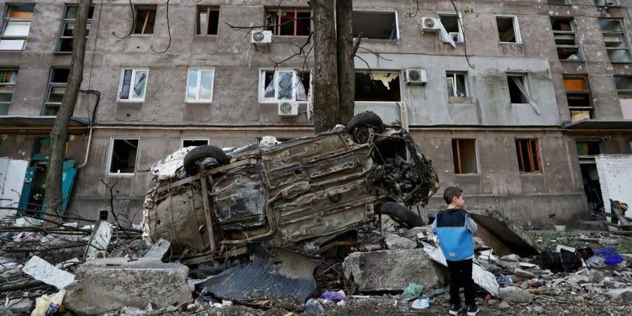 A boy stands near a building in Mariupol, destroyed by Russian shelling