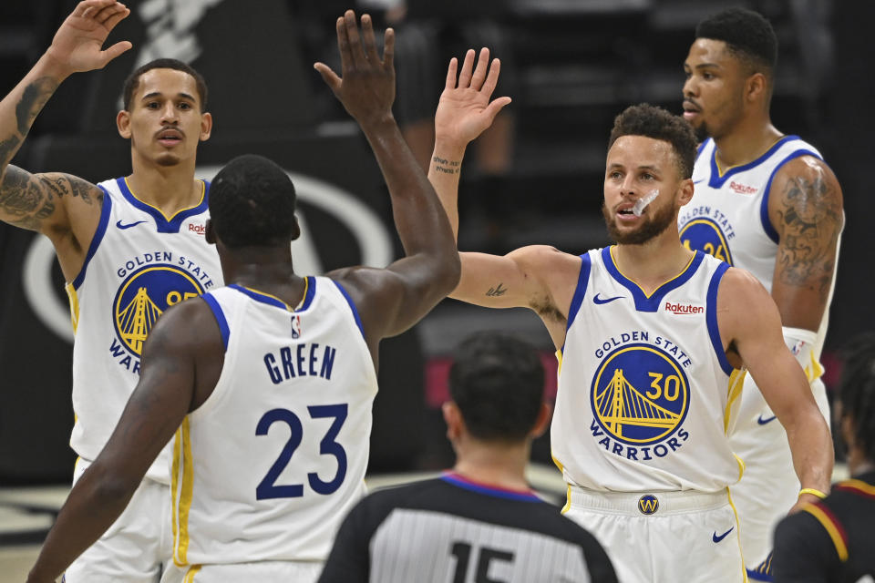 Golden State Warriors' Stephen Curry (30) and Draymond Green (23) celebrate before being substituted out of an NBA basketball game in the second half against the Cleveland Cavaliers, Thursday, April 15, 2021, in Cleveland. (AP Photo/David Dermer)