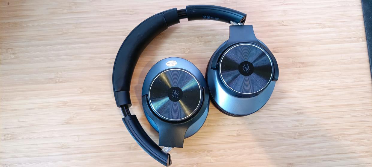  A pair of black and grey OneOdio A10 headphones sitting on a wooden desk. 