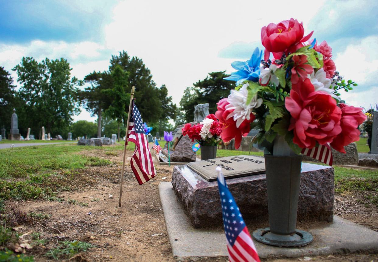 The American flag and flowers are on shown near a grave at the Gypsum Hill cemetery.