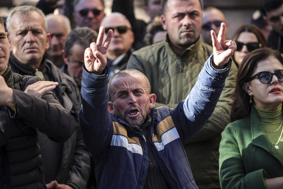 A supporter of the center-right Democratic Party shows the V-sign during an anti-government rally outside the Parliament building in Tirana, Albania, Monday, Dec. 18, 2023. Albanian opposition have protested against the government's it accuses of corruption while a parliamentary commission discusses on immunity for its leader Sali Berisha. (AP Photo/Armando Babani)